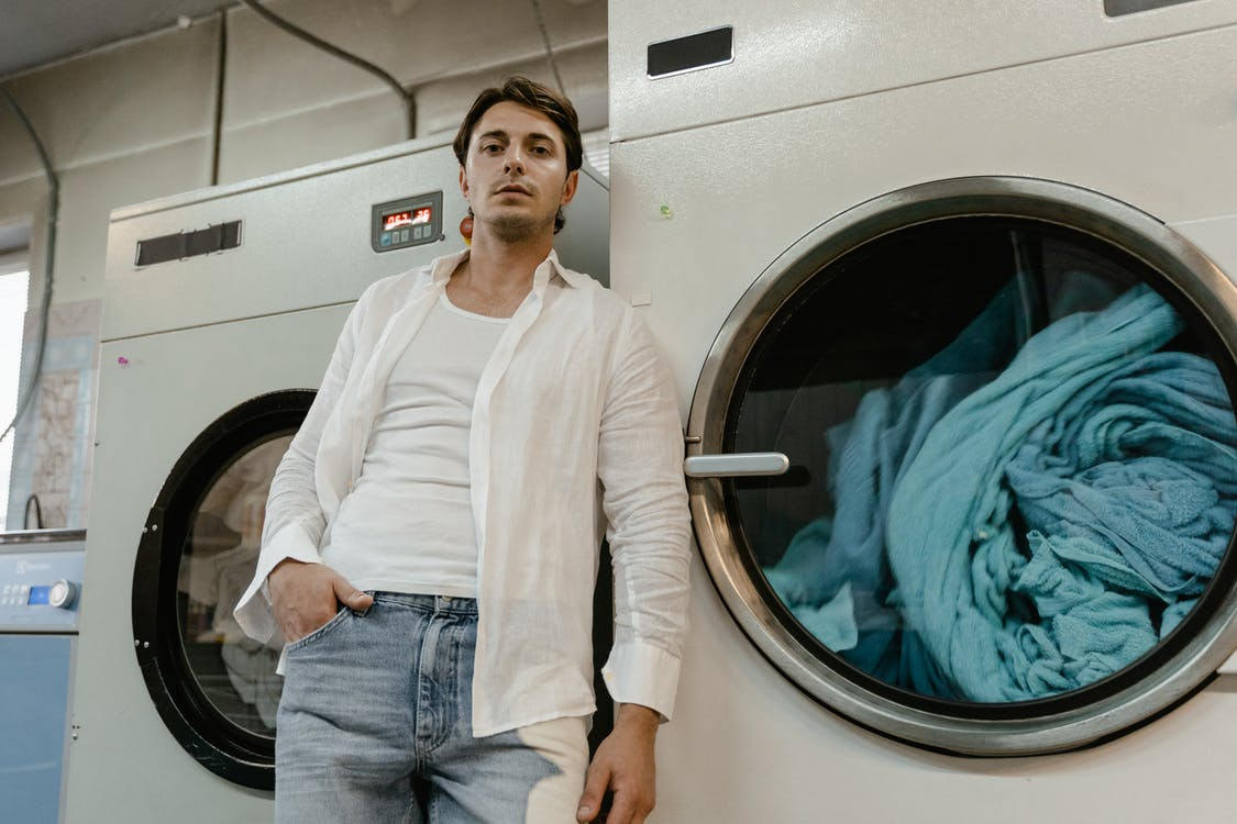 a-man-leaning-on-a-washing-machine